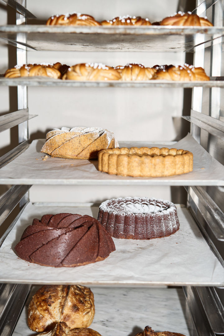 Hier sehen Sie einen Ständer mit Backblechen mit einer Auswahl von Lilians Backwaren, welche von verschiedenen Brotsorten über Kuchen bis zu ihren berühmten schwedischen Zimtschnecken reichen.